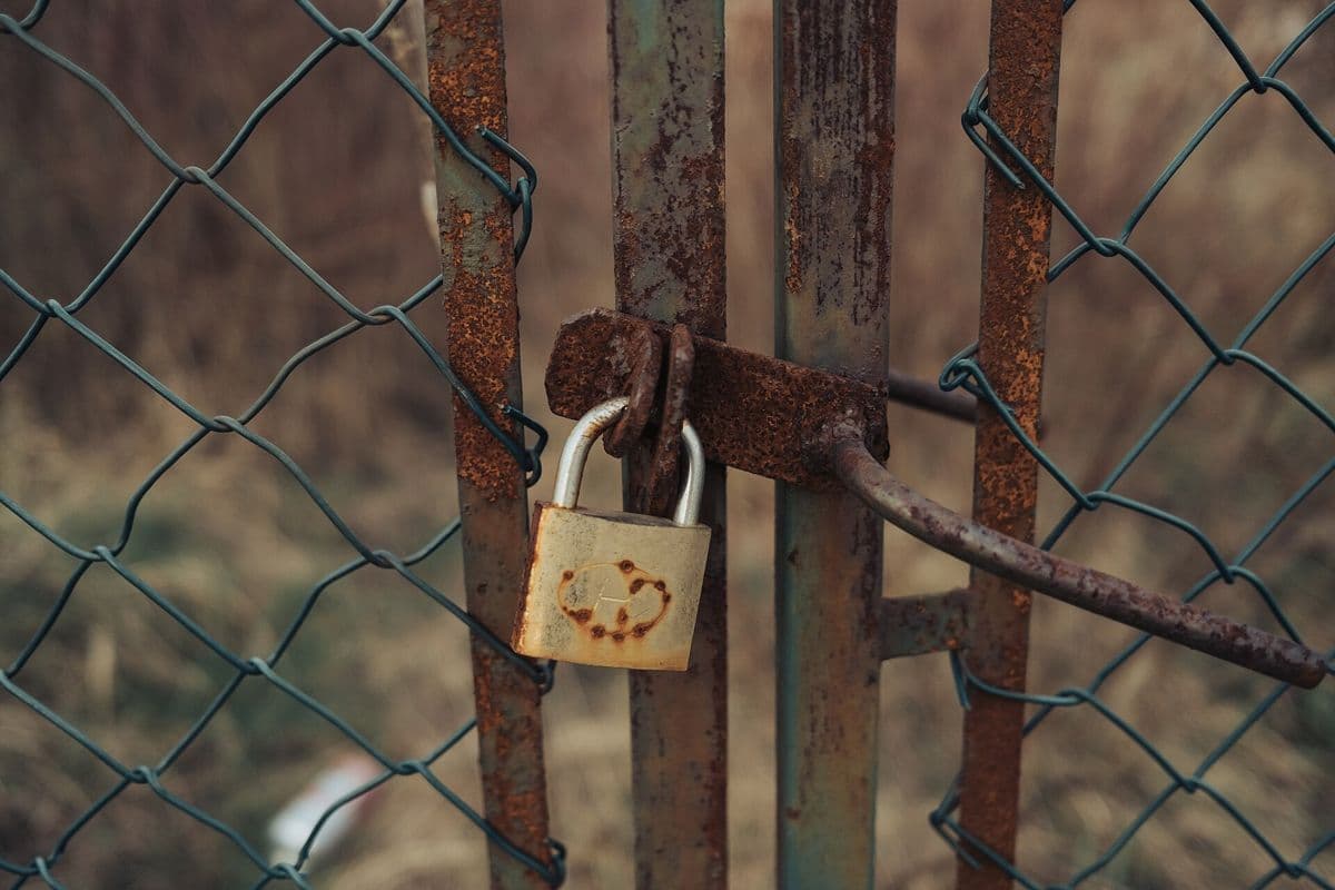 A weathered padlock securing a metal gate.