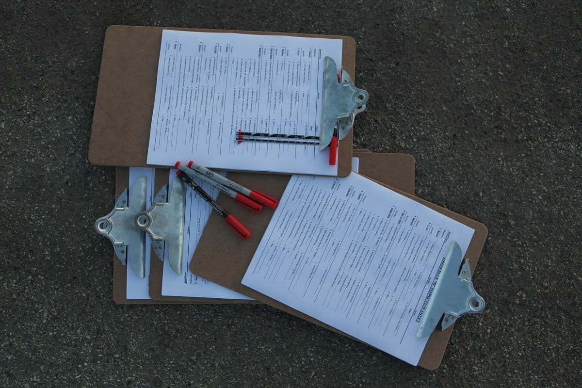 Clipboards holding printed checklists with pens.